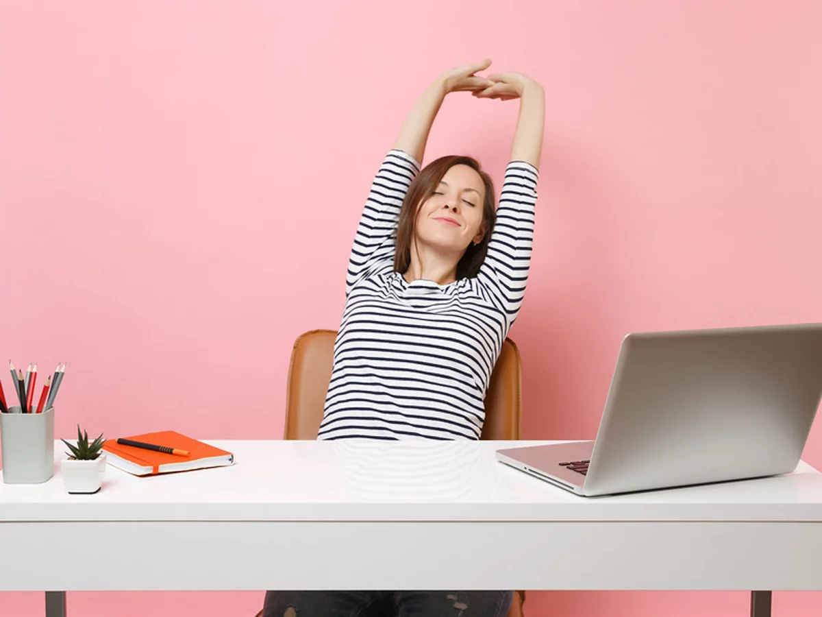 a woman stretching at her desk