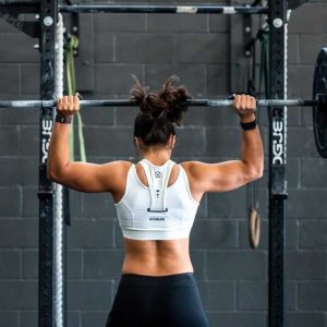 a woman doing overhead press with a barbell