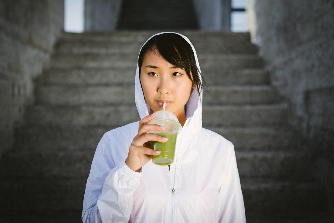 woman drinking a green snmoothie