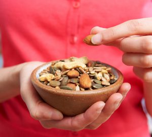 Close Up Of Woman Eating Bowl Of Healthy Nuts And Seeds