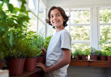 a young child standing by some indoor plants