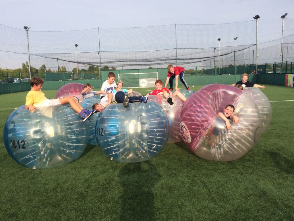 a group of kids playing in zorb balls