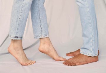 a couple facing each other in bare feet and jeans