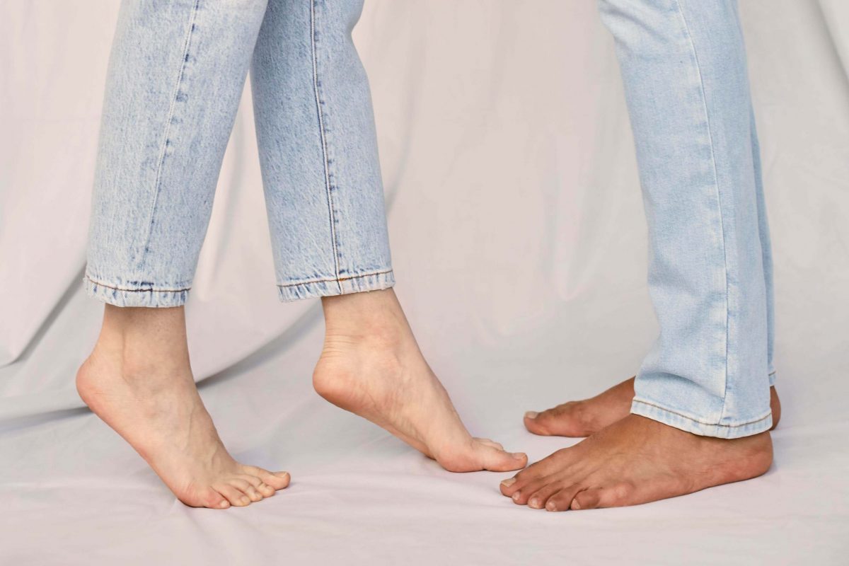 a couple facing each other in bare feet and jeans