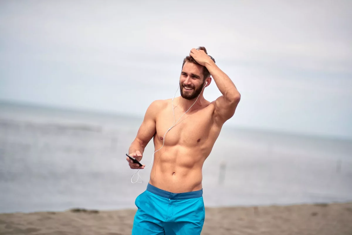 a man with no shirt at the beach