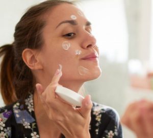 a woman applying skincare products to her face