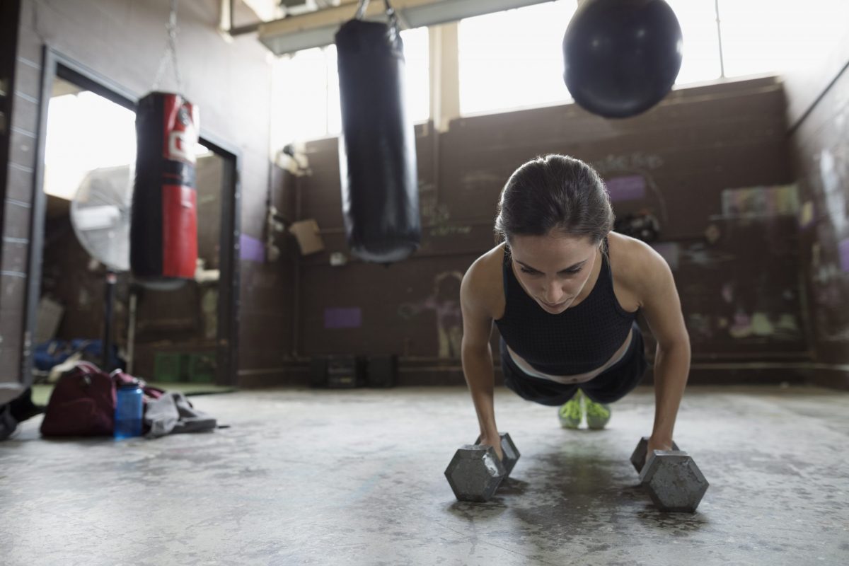 a woman doing dumbell pushups on the floor.