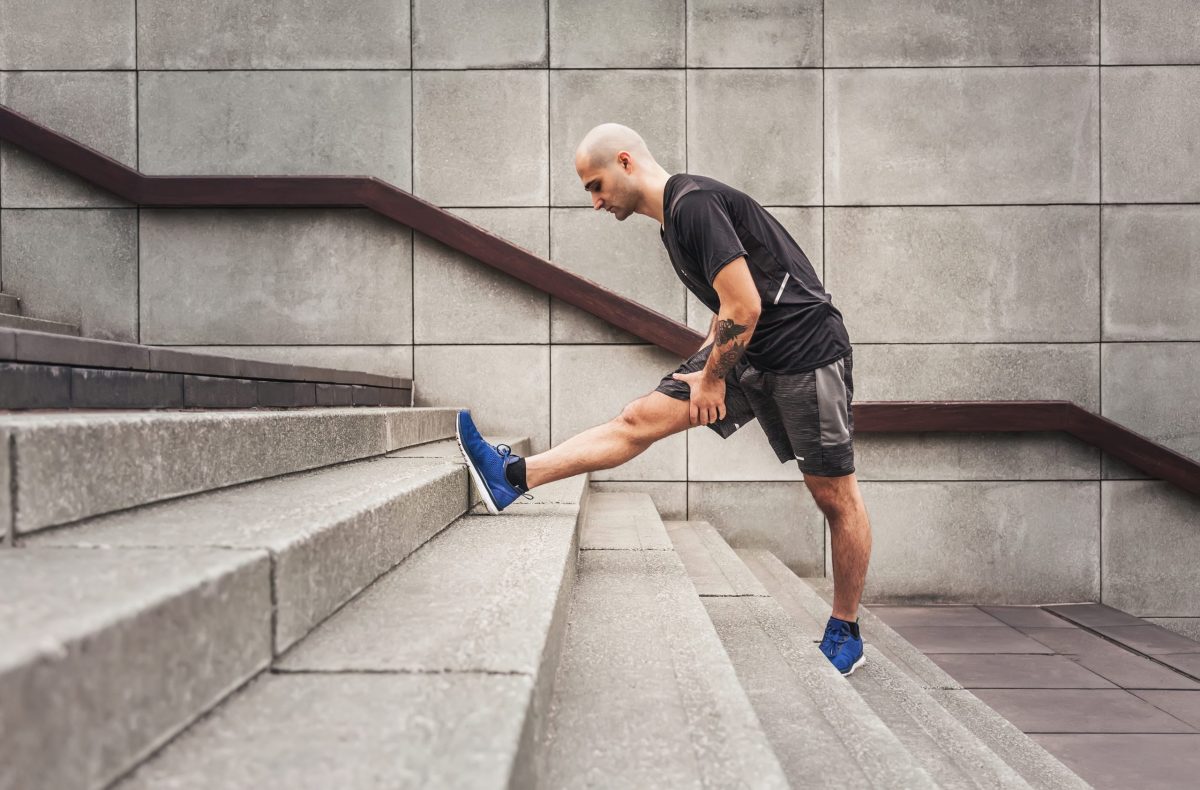 a man doing a hamstring stretch on some stairs