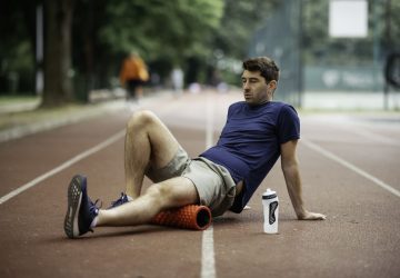a man foam rolling his legs on a track