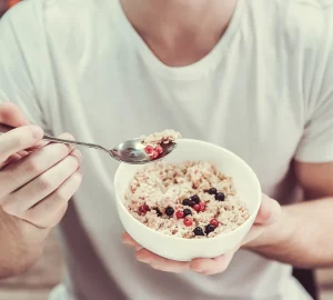 a man eating a bowl of oatmeal with berries