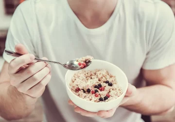 a man eating a bowl of oatmeal with berries